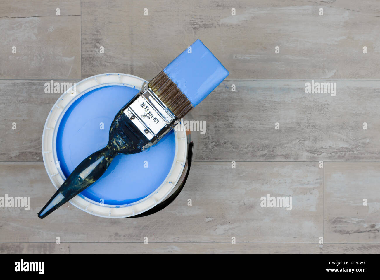 Können Sie blaue Farbe mit einem geladenen Pinsel Stand auf einem Holzboden shabby Stil Stockfoto