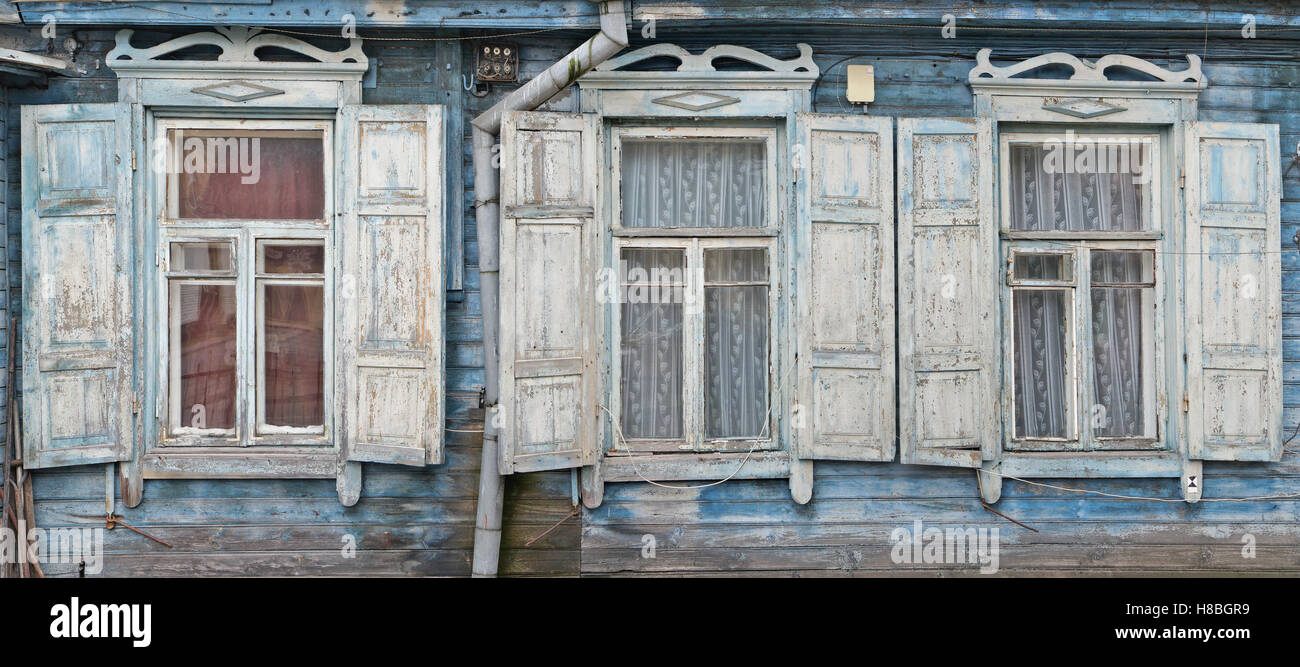 Drei Fenster mit einer offenen Sonnenblenden im alten zerstörten blau Retro-Holzhaus. Panorama Collage aus mehreren Fotos Stockfoto