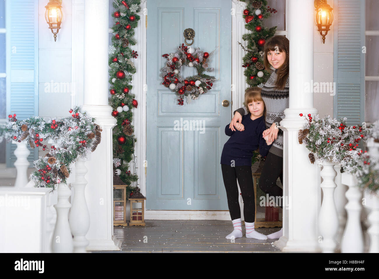 Mutter und Tochter in gemütliches Zuhause, dekoriert Eingang zum Haus mit hellen Farben. Familie Neujahr warten. Familie Weihnachten Stockfoto