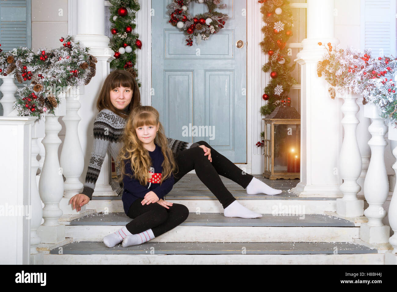 Mutter und Tochter in gemütliches Zuhause, dekoriert Eingang zum Haus mit hellen Farben. Familie Neujahr warten. Familie Weihnachten Stockfoto