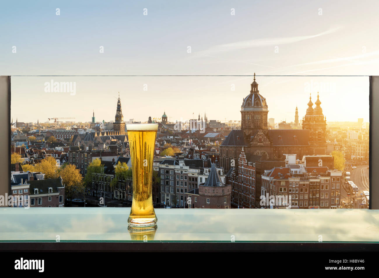 Bier und Schaum Bier am Tisch in der Bar auf der Dachterrasse mit Amsterdam Skyline im Hintergrund in Amsterdam, Niederlande. Stockfoto
