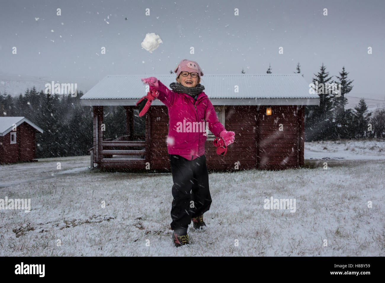 Ein Mädchen wirft einen Schneeball während eines Schneesturmes außerhalb Kirkjubaejarklaustur im Südosten von Island Stockfoto