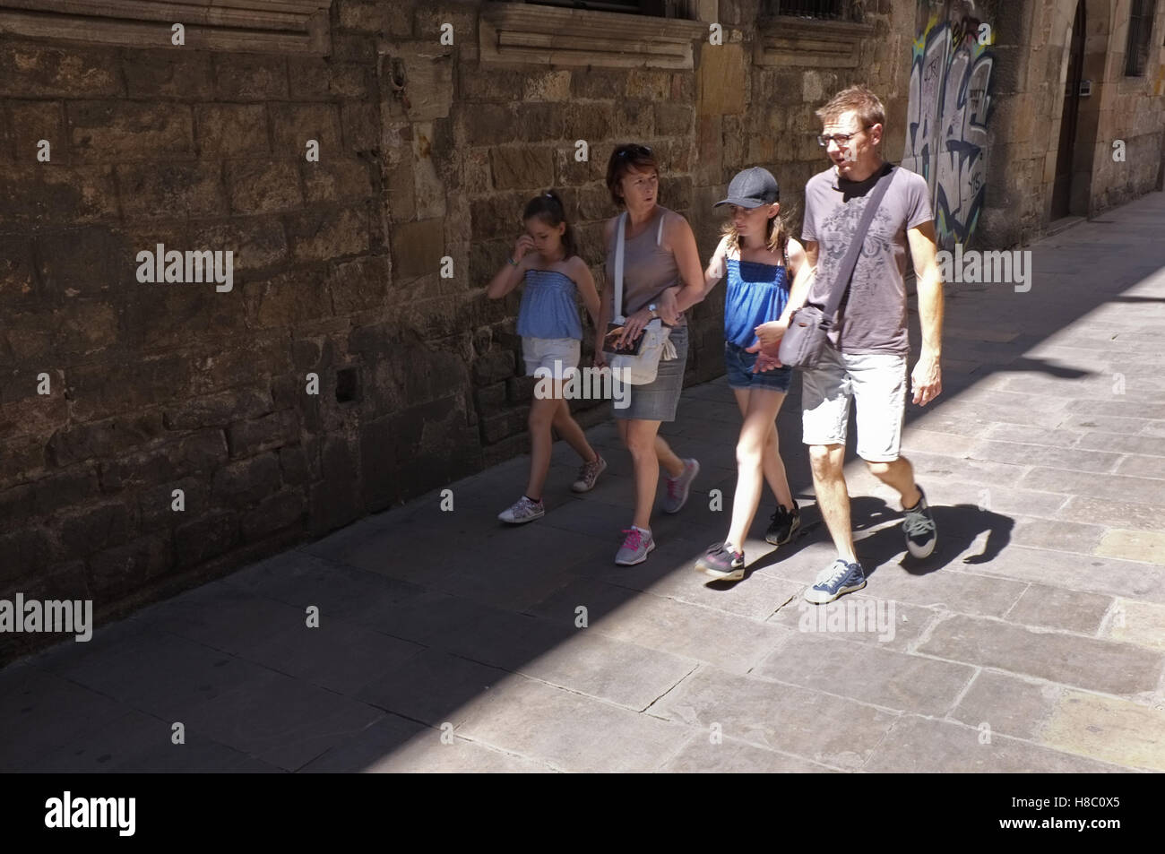 Eine Familie, die zu Fuß durch die Straßen von Barcelona an einem heißen Sommertag Stockfoto