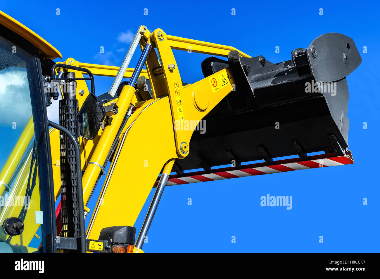 Leuchtend gelbe Traktor-Loader auf einem Hintergrund von den klaren blauen Himmel, Kabine mit der angehobenen Pfanne hautnah Stockfoto