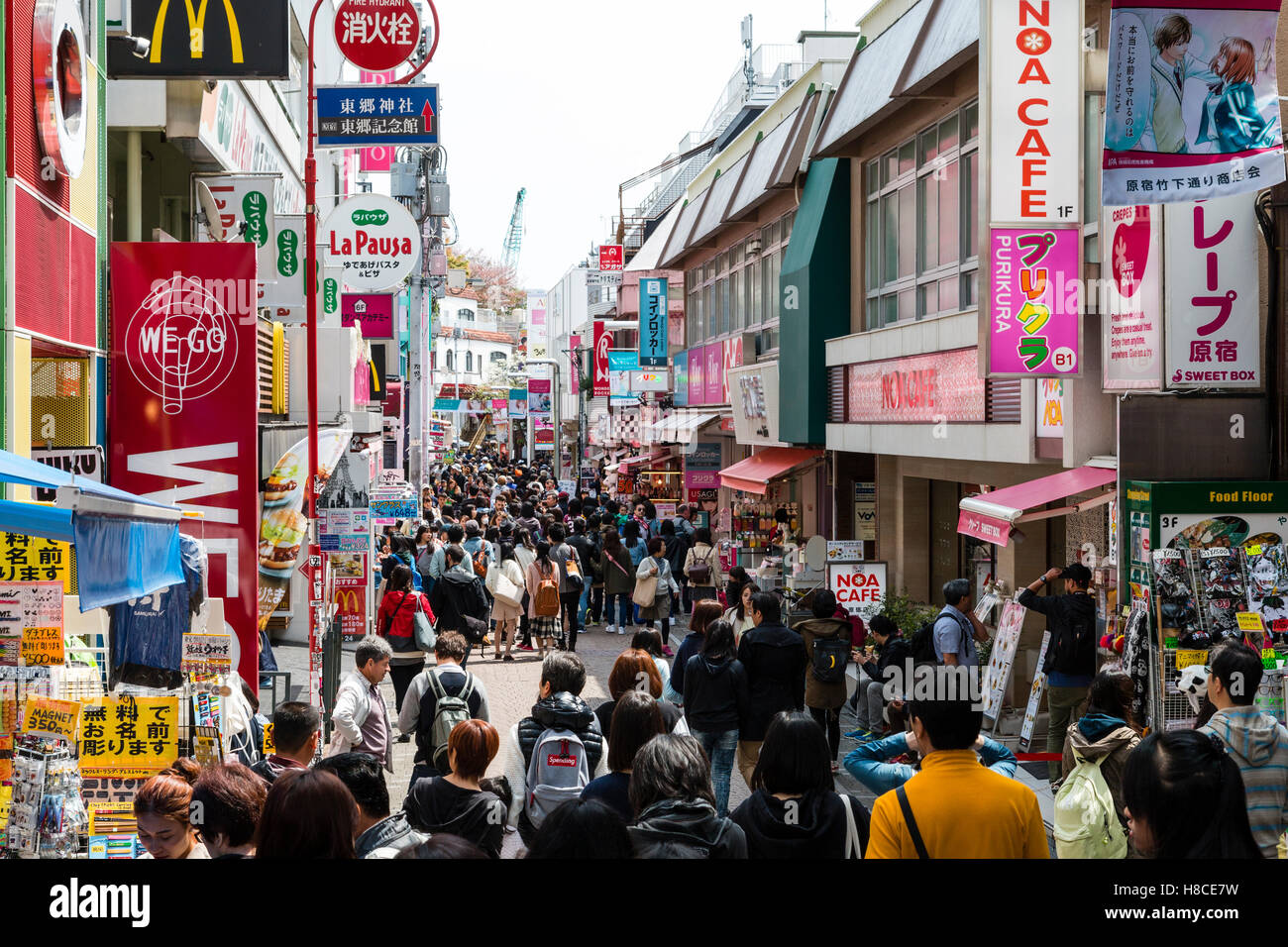 Japan, Tokio, Harajuku. Blick entlang der Fußgängerzone Takeshita Straße mit Menschen am Mittag, von McDonalds und kleine Boutiquen und Geschäften voll. Stockfoto