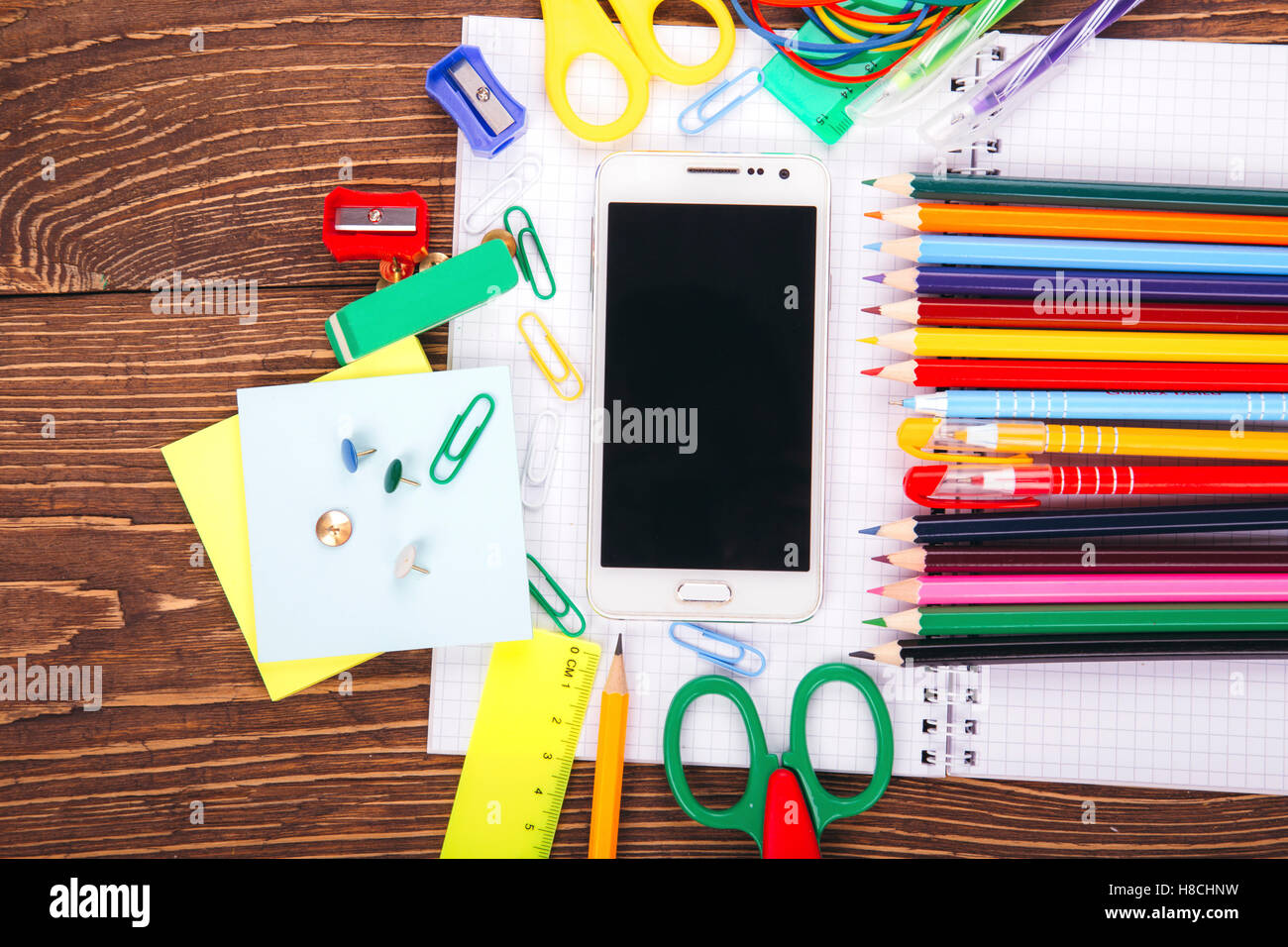 Offene leere Notebook liefert weißen Smartphone mit Rahmen der Schule auf einem Holztisch Hintergrund. Zurück zum Schulkonzept. Stockfoto