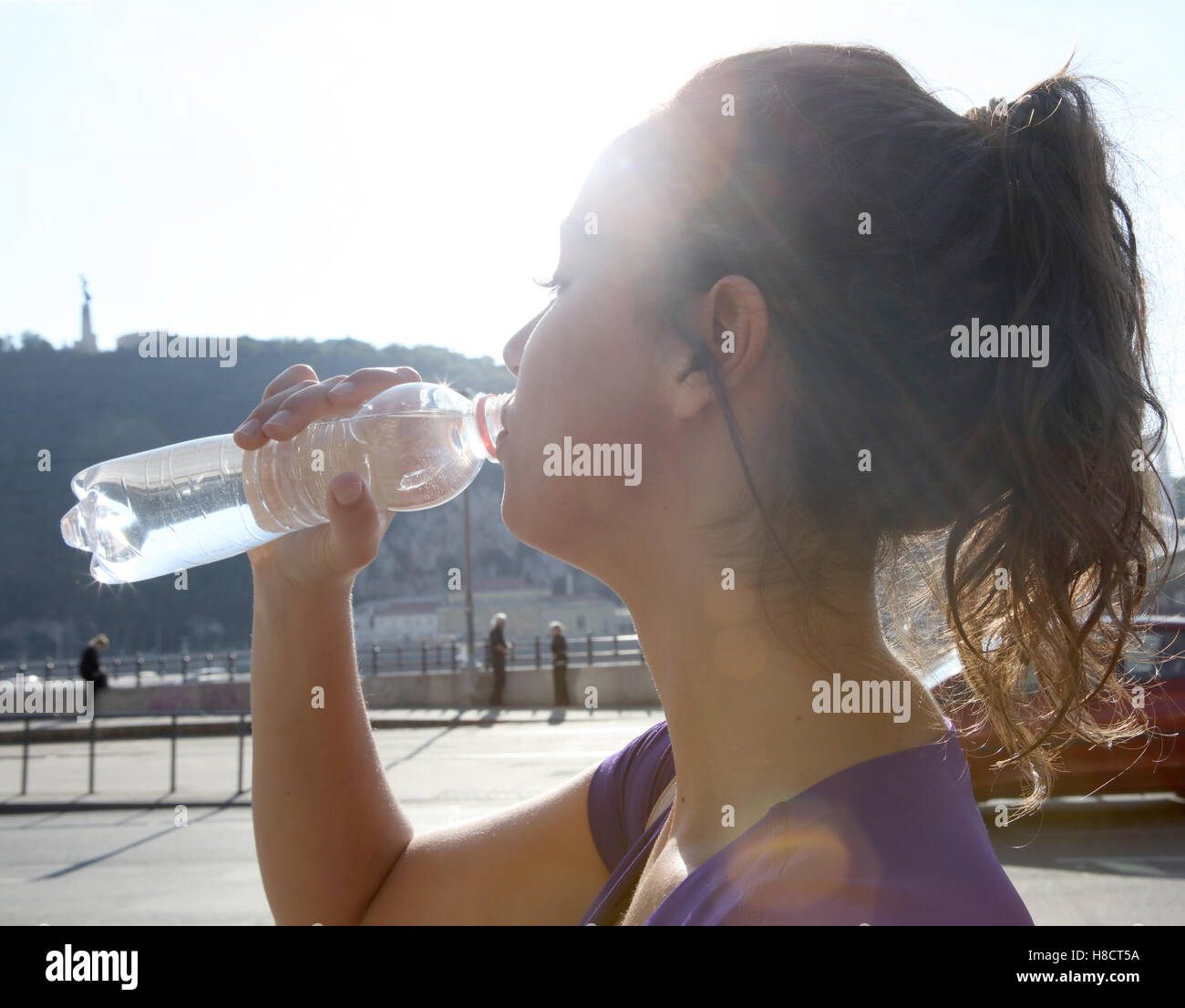 Junge Frau Trinkwasser im Sonnenschein Stockfoto