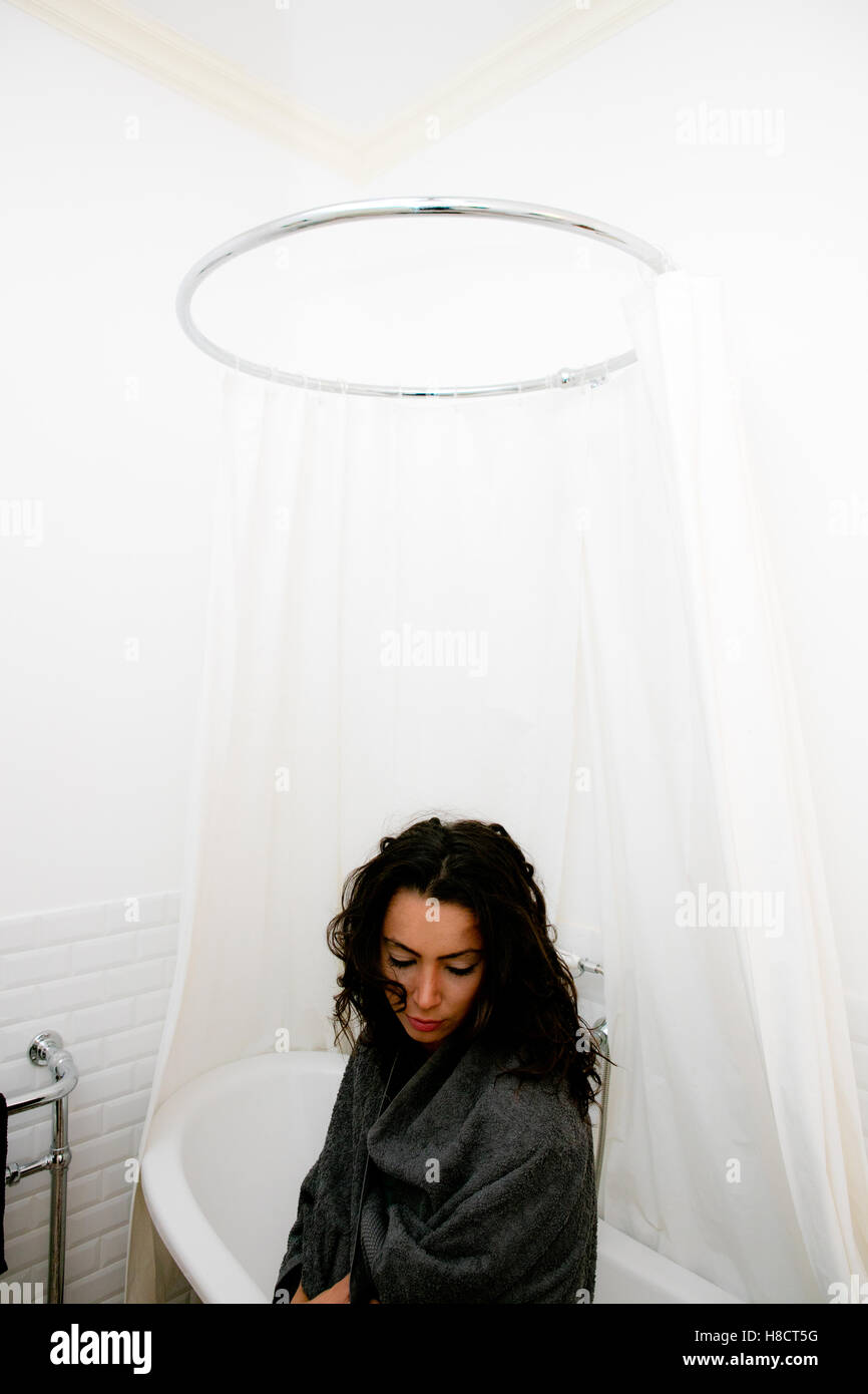 junge Frau sitzt am Rand des Bades in Luxus-Badezimmer Leben betrachten Stockfoto