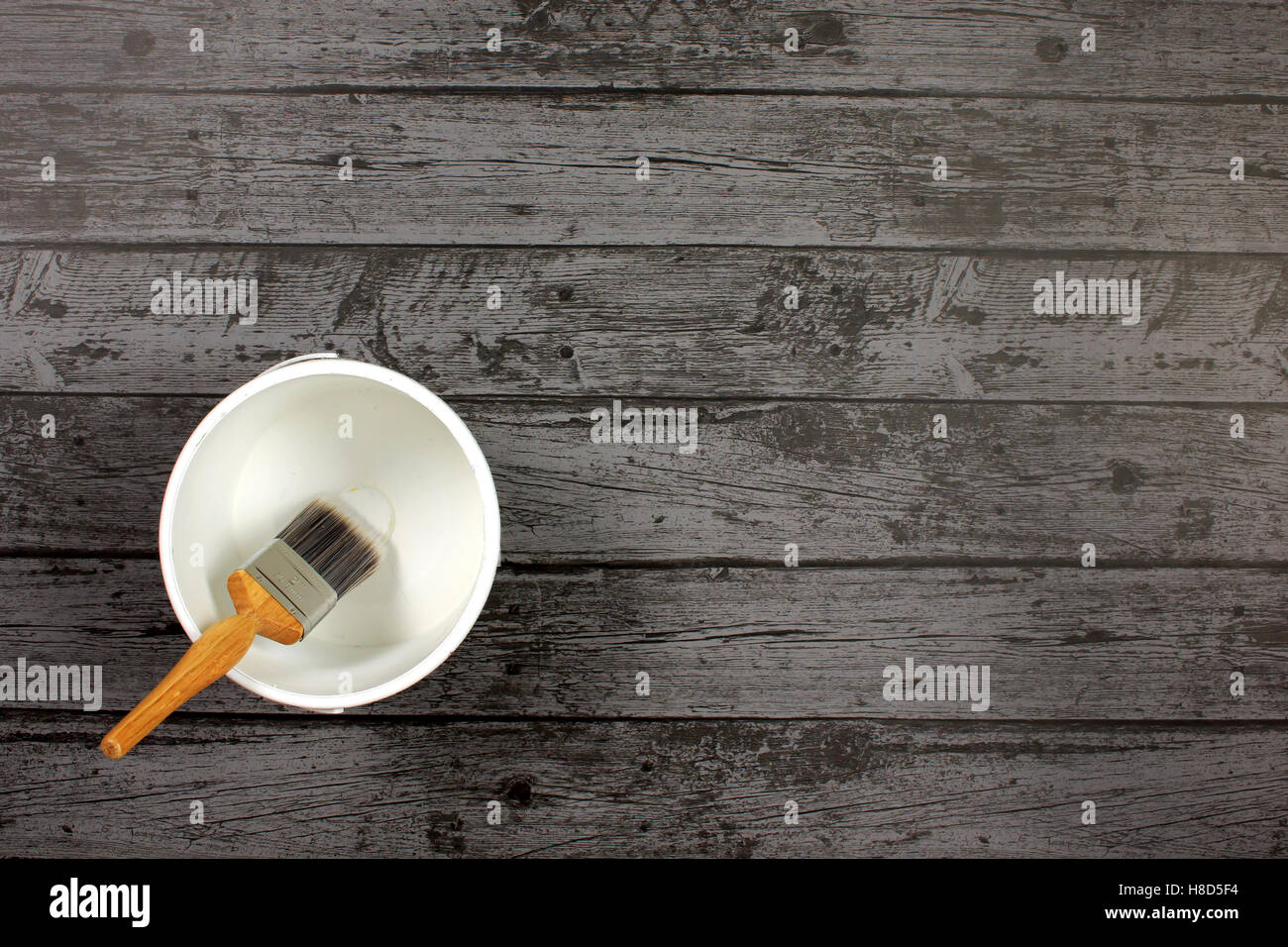 Pinsel, sitzen in einem leeren Weißlack Kessel gefüllt auf einem dunklen grauen Boden-Internat Stockfoto