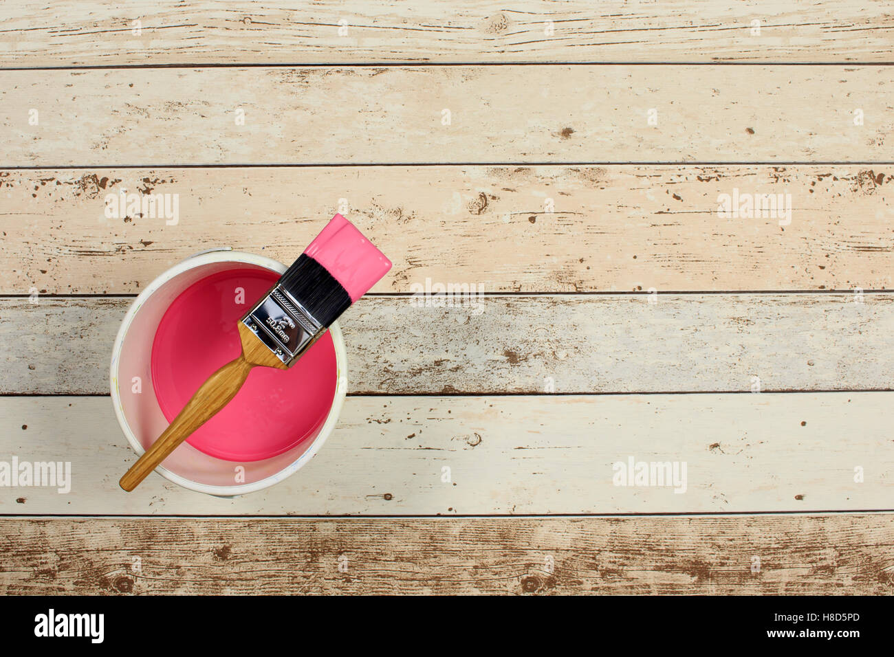 Geladenen Pinsel über eine weiße Farbe Wasserkocher gelegt gefüllt mit rosa Farbe und hellen bunten Boden einsteigen Stockfoto