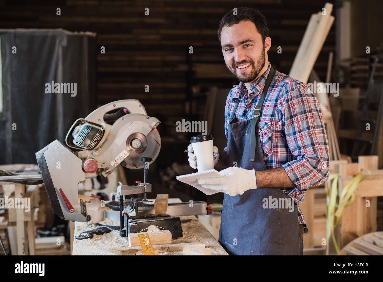 Zimmermann, eine Kaffee-Pause halten Notebook vor Kreissäge in seiner Werkstatt Stockfoto