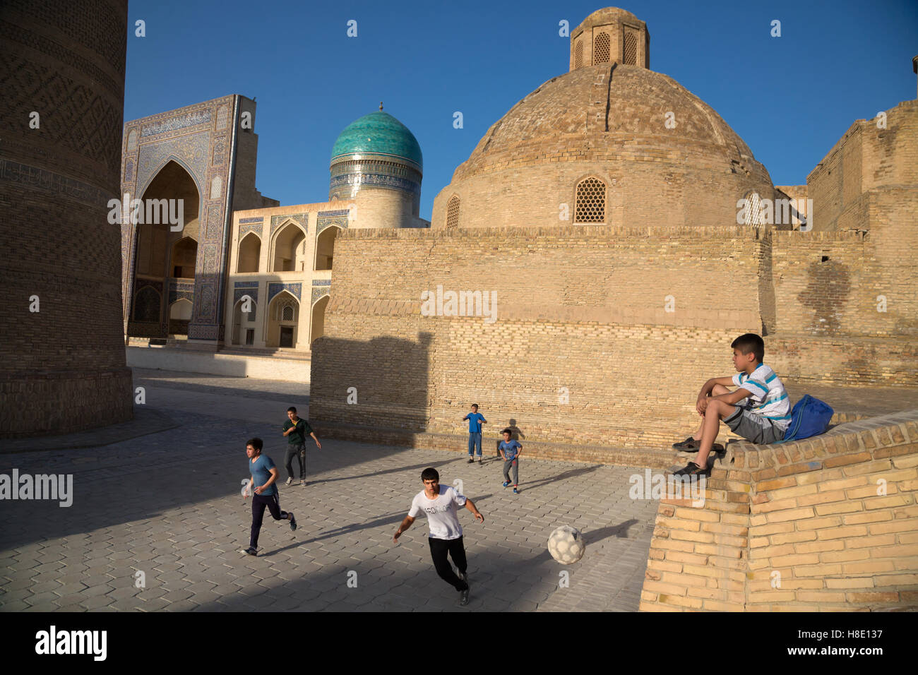 Jugendliche Kinder spielen Fußball, der von Sonnenuntergang in der antiken Stadt Buchara, Usbekistan - Reisefotos Seidenstraße Stockfoto