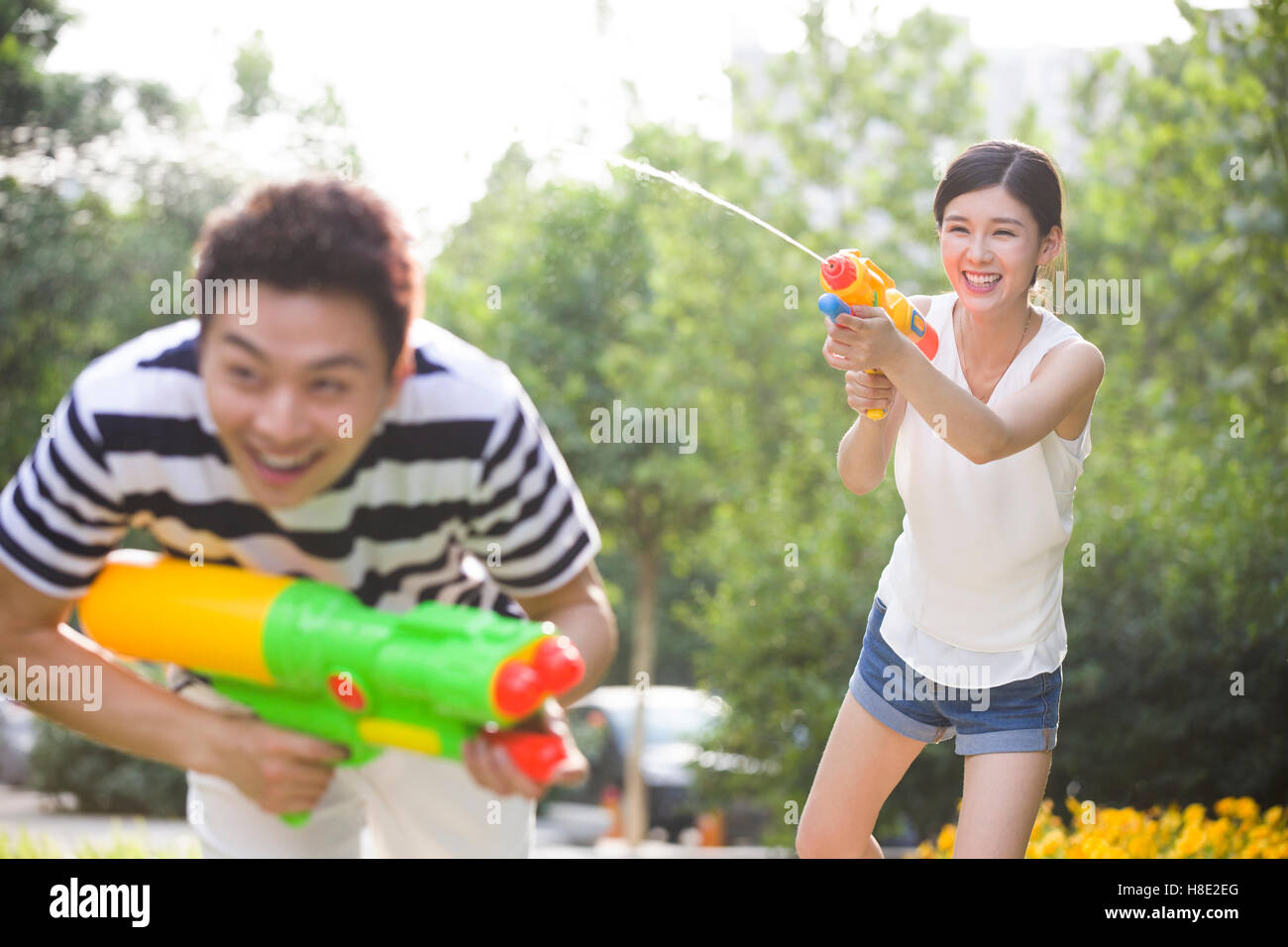 Glückliche junge chinesische paar spielen Spritzpistolen Stockfoto