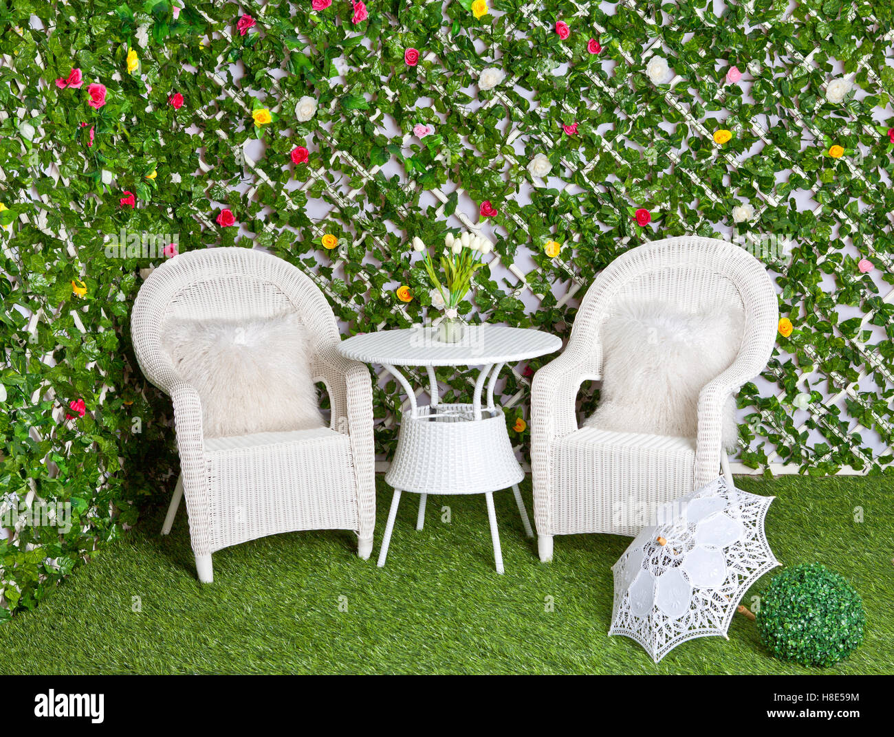 Weiße Korbmöbel Rattan im blühenden Garten. Vintage Maßwerk Regenschirm  Stockfotografie - Alamy