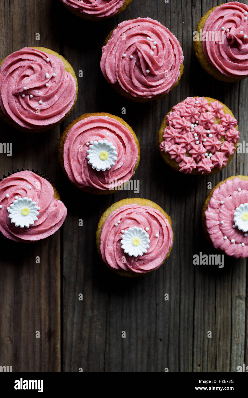 Rosa Geeiste Muffins auf einem Vintage Brett mit Blumen Stockfoto