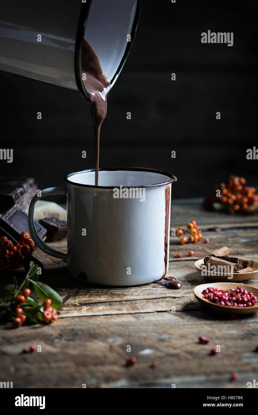 Heißen Schokolade in einem Becher auf Holztisch gießen Stockfoto