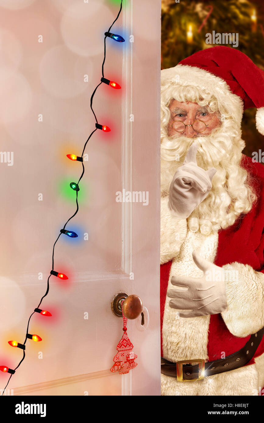 Santa Claus an einer offenen Tür Weihnachten mit Lichterketten dekoriert Stockfoto