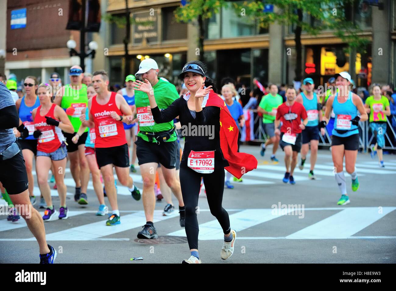 In der Flagge ihres Landes drapiert, Fan Zhang China Verhandlungen über einen Kurs drehen während des Chicago Marathon 2016. Chicago, Illinois, USA. Stockfoto