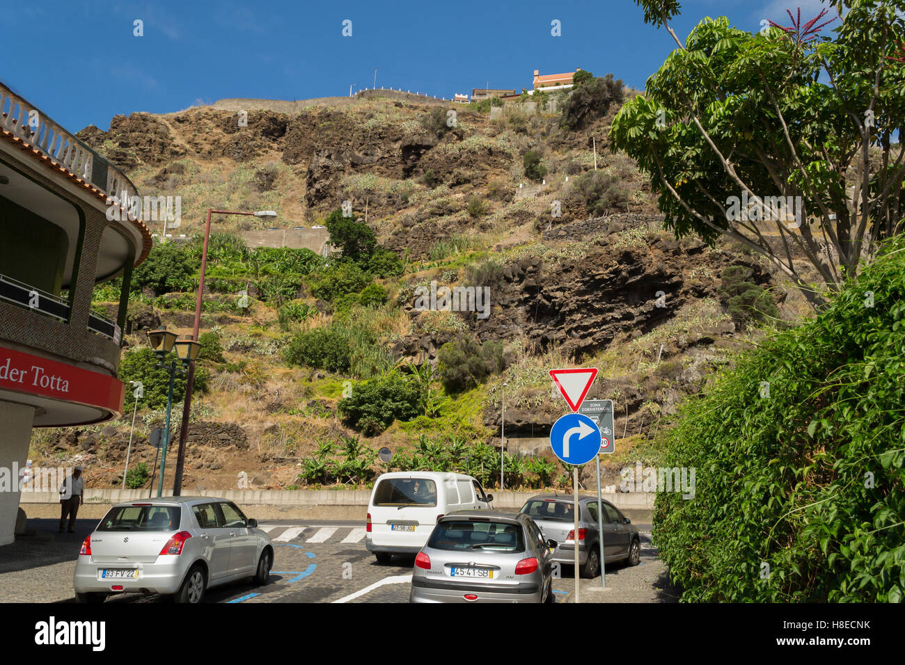 Zeigen Sie auf der normalen Straße in der kleinen Stadt, steilen Hügel in der Ferne mit dem Bau auf sie an Stockfoto