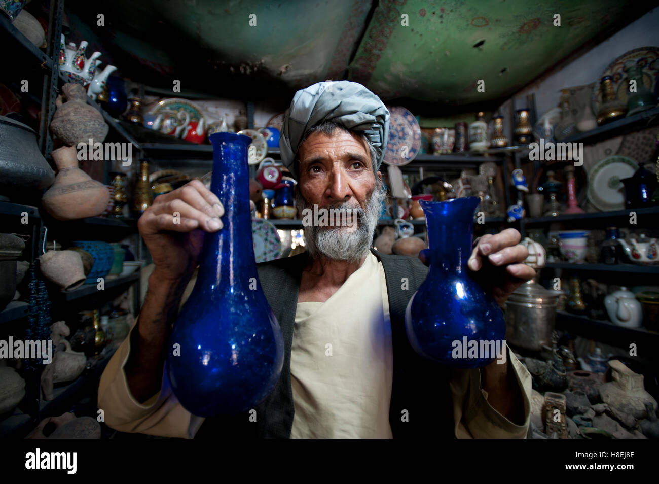 Ein Glasbläser hält blauen Kürbis-förmigen Glasvasen in einem Schmuck-Shop in Herat, Afghanistan, Asien Stockfoto