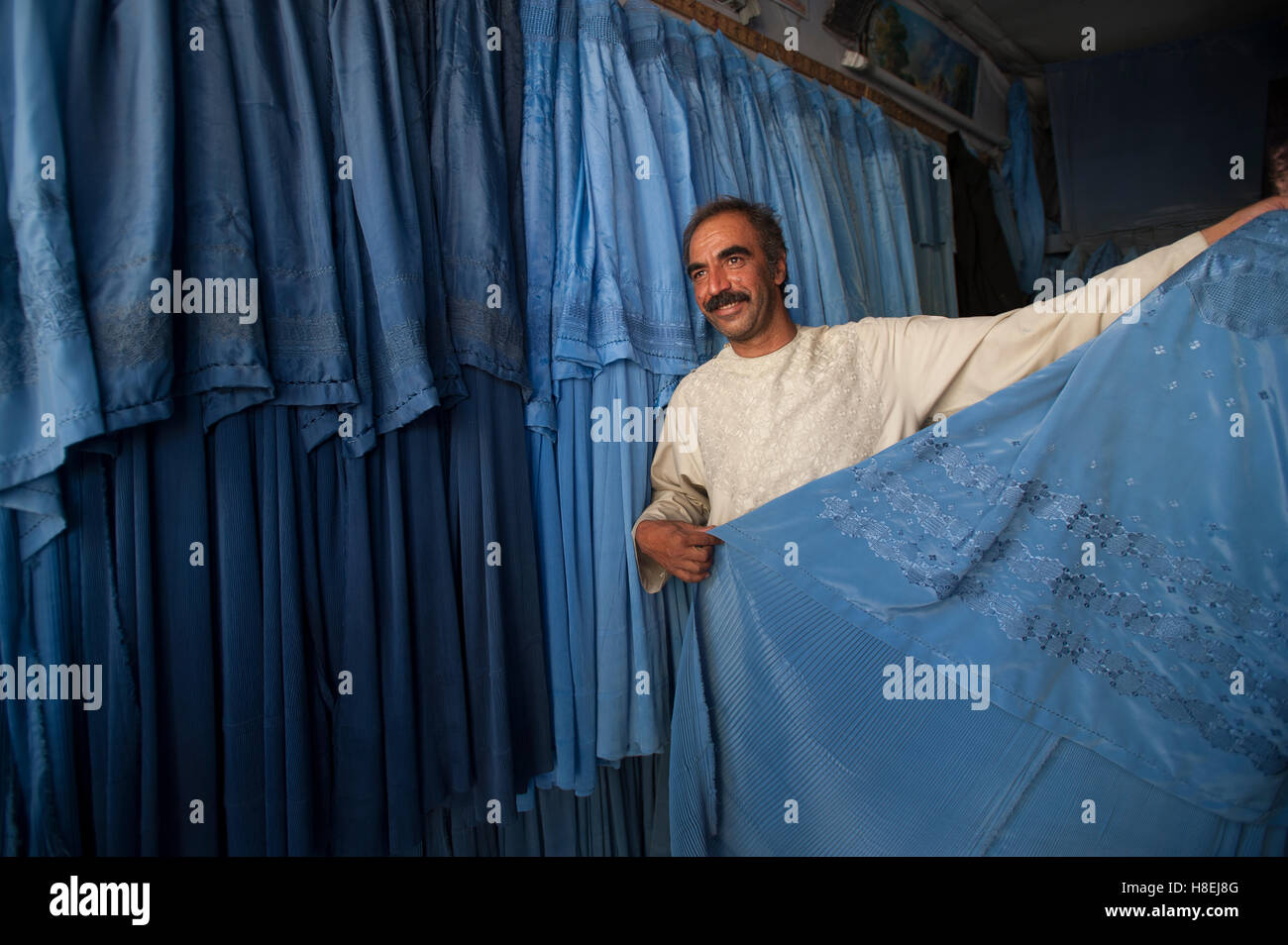 Ein Ladenbesitzer beweist, dass nicht alle Burkas identisch sind, Herat, Afghanistan, Asien Stockfoto