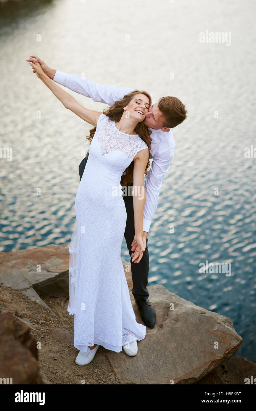 Braut und Bräutigam auf dem Hintergrund der Wasser umarmen Stockfoto
