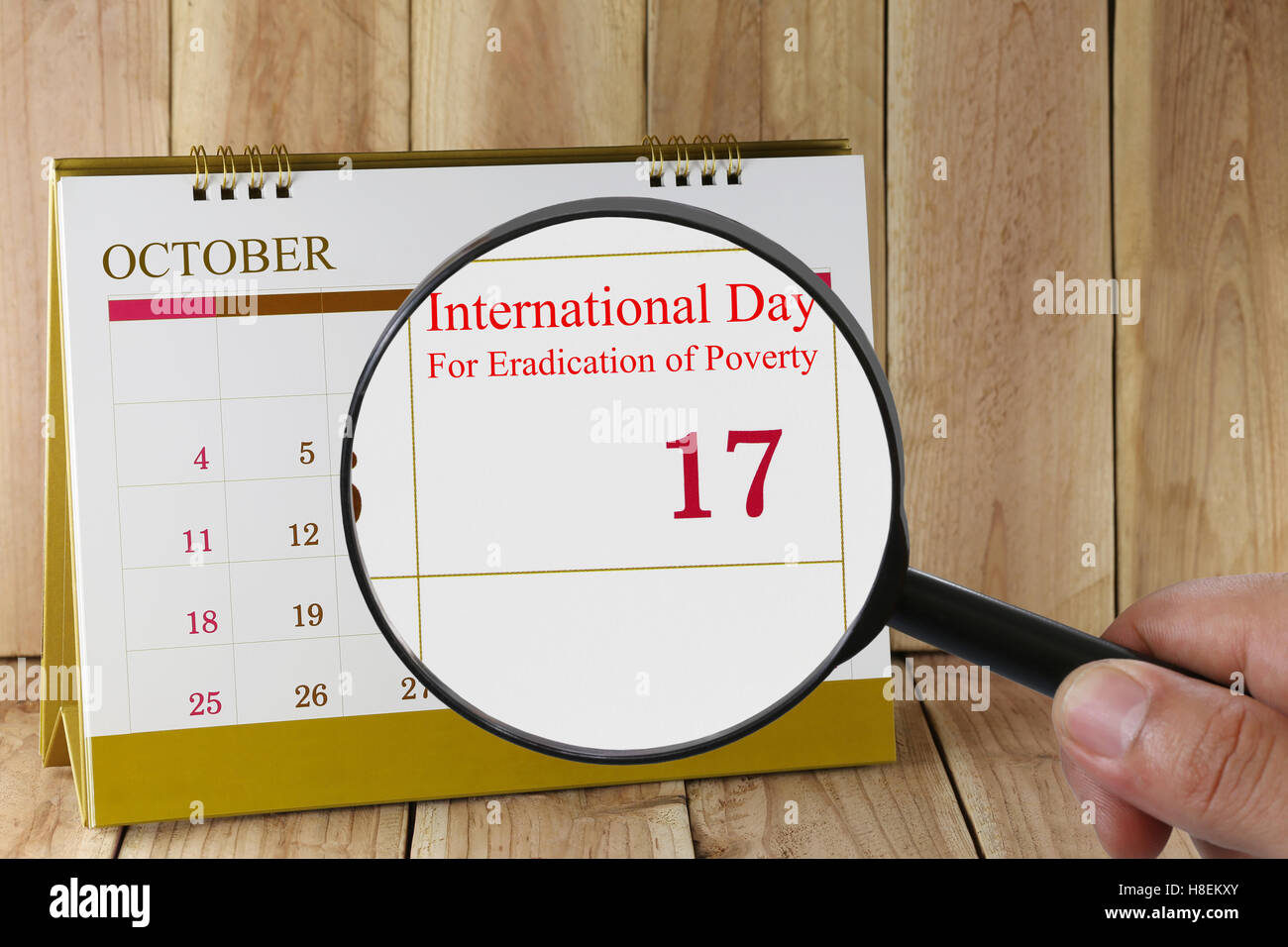 Lupe in der Hand im Kalender sehen Sie internationale Tag zur Beseitigung der Armut am 17. Oktober Konzept eines öffentlichen Stockfoto