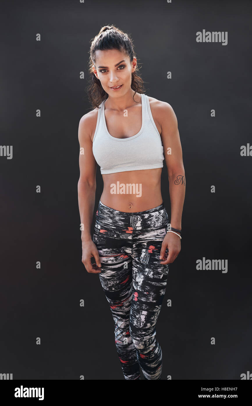 Porträt von Fit junge Frau in Sportkleidung Kamera stehend auf schwarzem Hintergrund zu betrachten. Muskuläre Fitness-Modell. Stockfoto