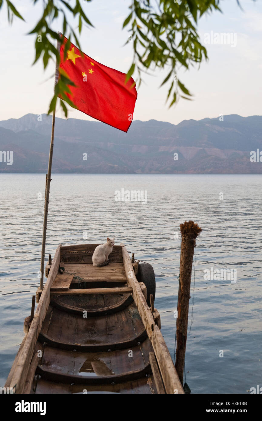 Holzboot mit chinesischen Flagge und eine Katze am Lugu-See, China, Asien Stockfoto