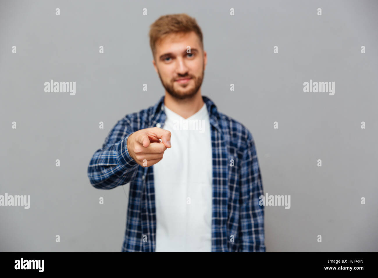 Porträt von einem gutaussehenden Mann Zeigefinger in die Kamera auf einem grauen Hintergrund isoliert Stockfoto
