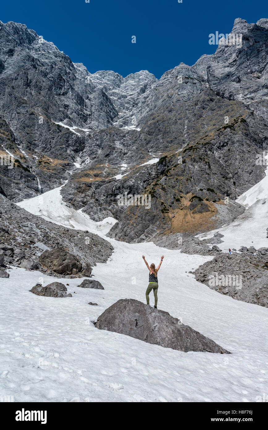 Wanderer auf Felsen mit Arme ausgestreckt, deutschen Alpen tiefsten Schneefeld, Watzmann-Ostwand, Berchtesgaden, Bayern Stockfoto