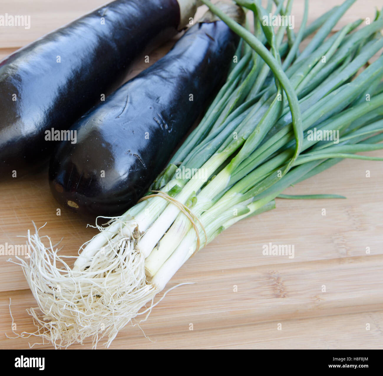 Aubergine mit Frühlingszwiebeln auf Schneidebrett Stockfoto