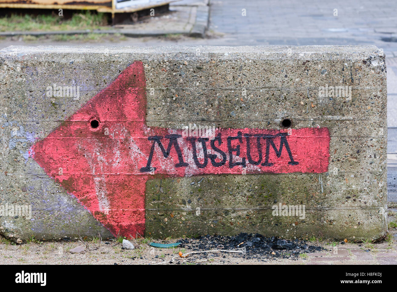 Amsterdam, Holland. "Museum" Grafitti auf einem Betonblock, der nach links zeigt. Stockfoto