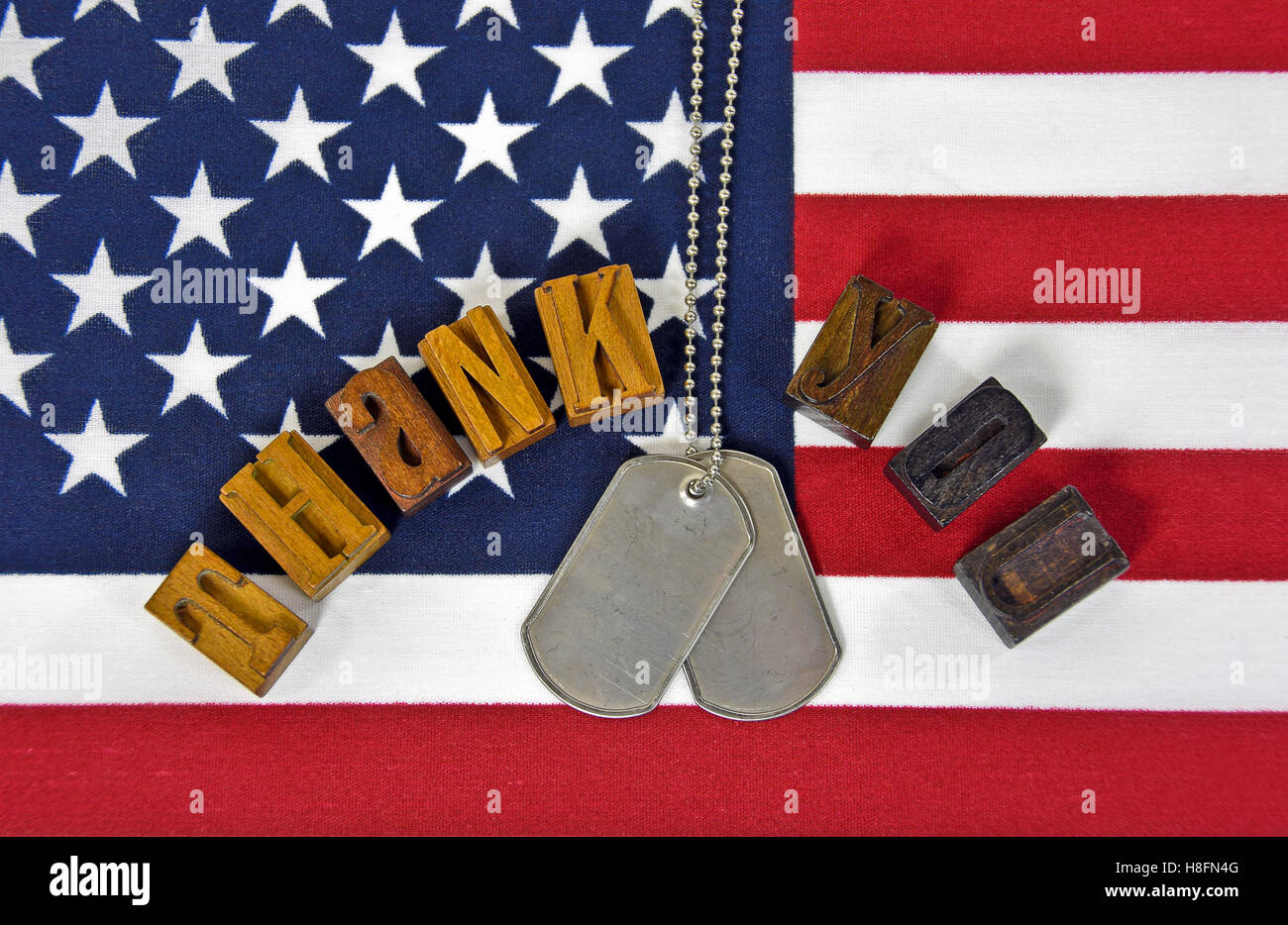 Vielen Dank an militärischen mit Erkennungsmarken und Vintage Holz Buchdruck Typ auf amerikanische Flagge Stockfoto