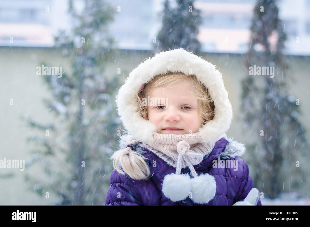 schöne blonde Mädchen spielen mit Schnee Stockfoto