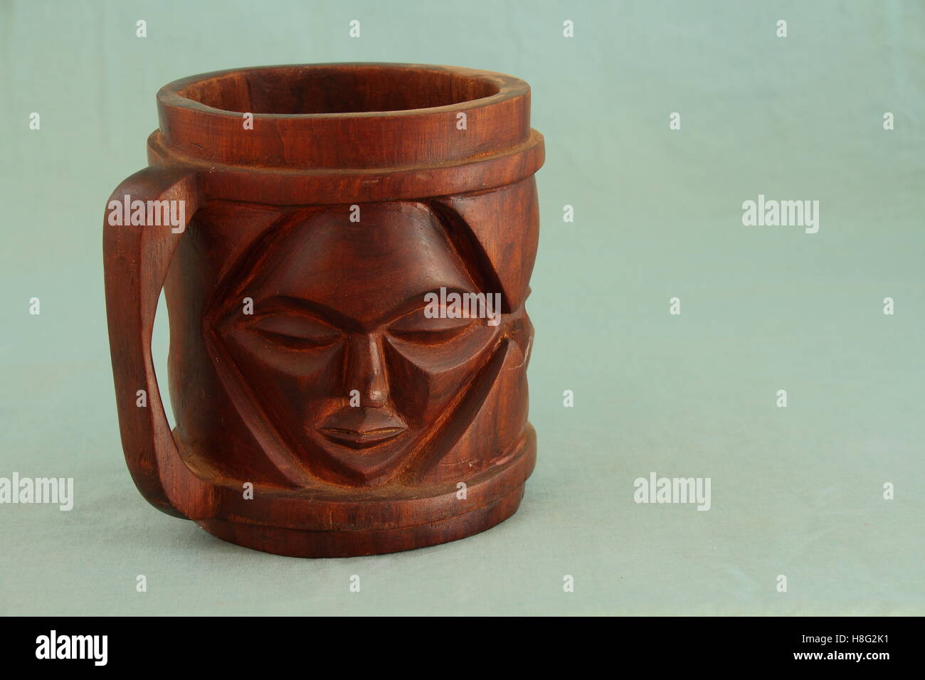 Afrikanische Kunst - ein dekorativer Krug aus Holz geschnitzt auf grünem Hintergrund Bild im Querformat mit Kopie Raum isoliert Stockfoto