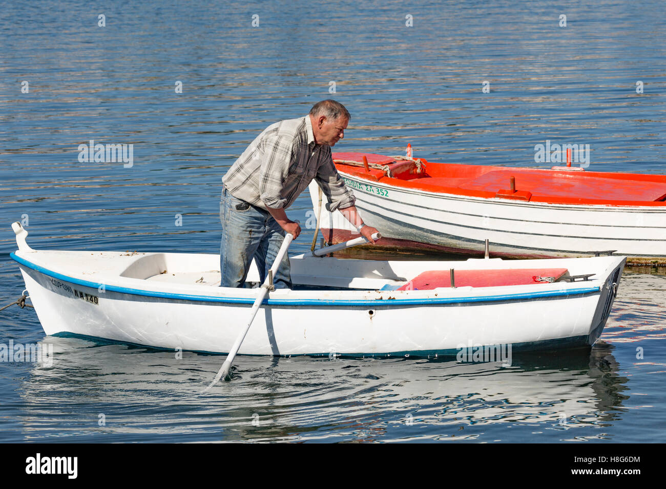 Ein griechischer Fischer ist sein Boot rudern. Stockfoto