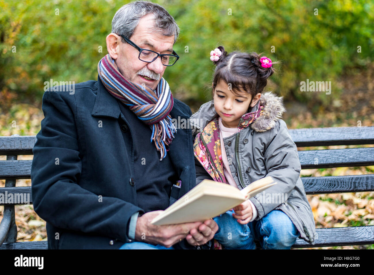 Großvater und Enkelin Lesen eines Buches im Herbst park Stockfoto