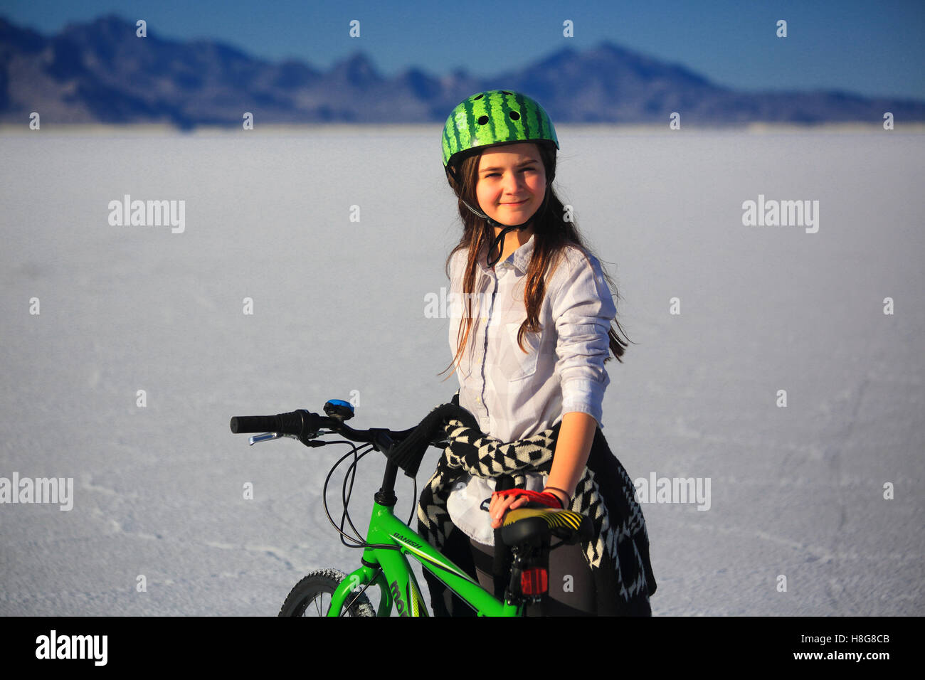 Eine Tween-Mädchen trägt einen Wassermelone Fahrradhelm hält ein lindgrün-Bike auf den Bonneville Salt Flats, Utah. Stockfoto