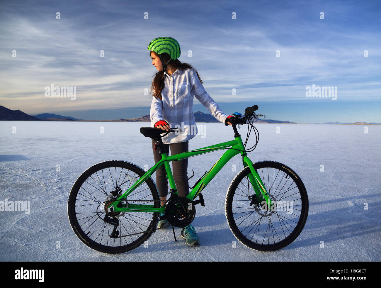 Eine Tween-Mädchen mit Wassermelone Fahrradsturzhelm streckt Lime green Mountainbike auf dem Salzsee von Bonneville in Utah. Stockfoto