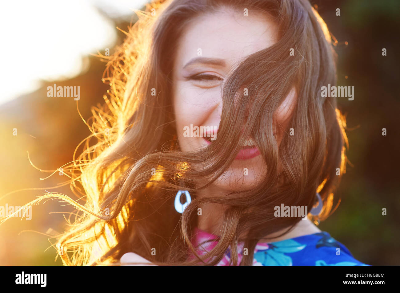 glückliche junge Frau posiert im Park gegen Sonnenuntergang Stockfoto