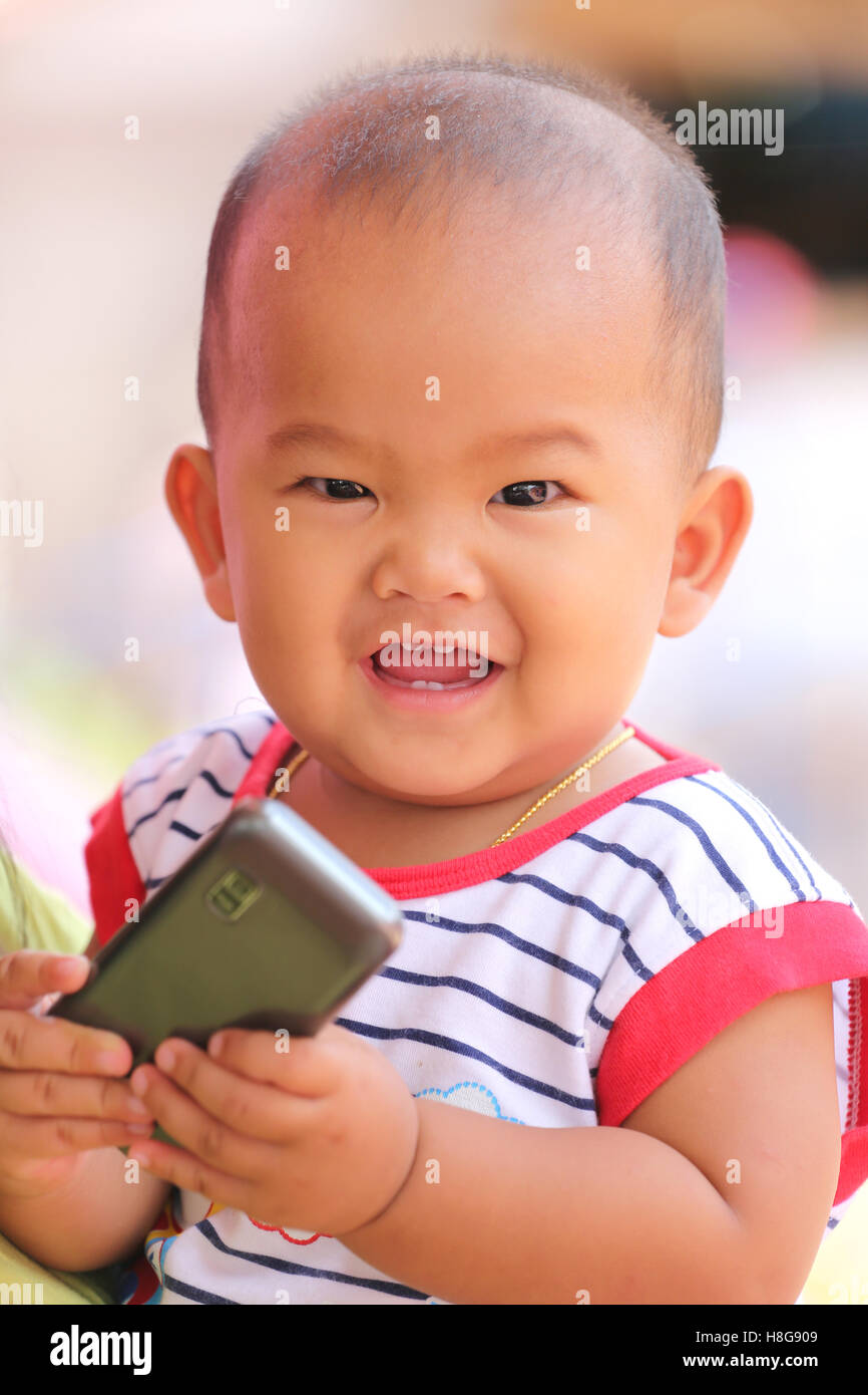 Asiatische baby ein Handy in der Hand halten und Lächeln mit glücklich, Konzept der Gesundheit und Entwicklung der Kinder. Stockfoto