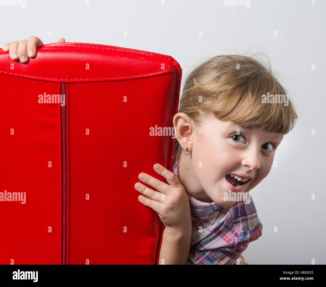 lustiges Mädchen mit roten Stuhl Stockfoto