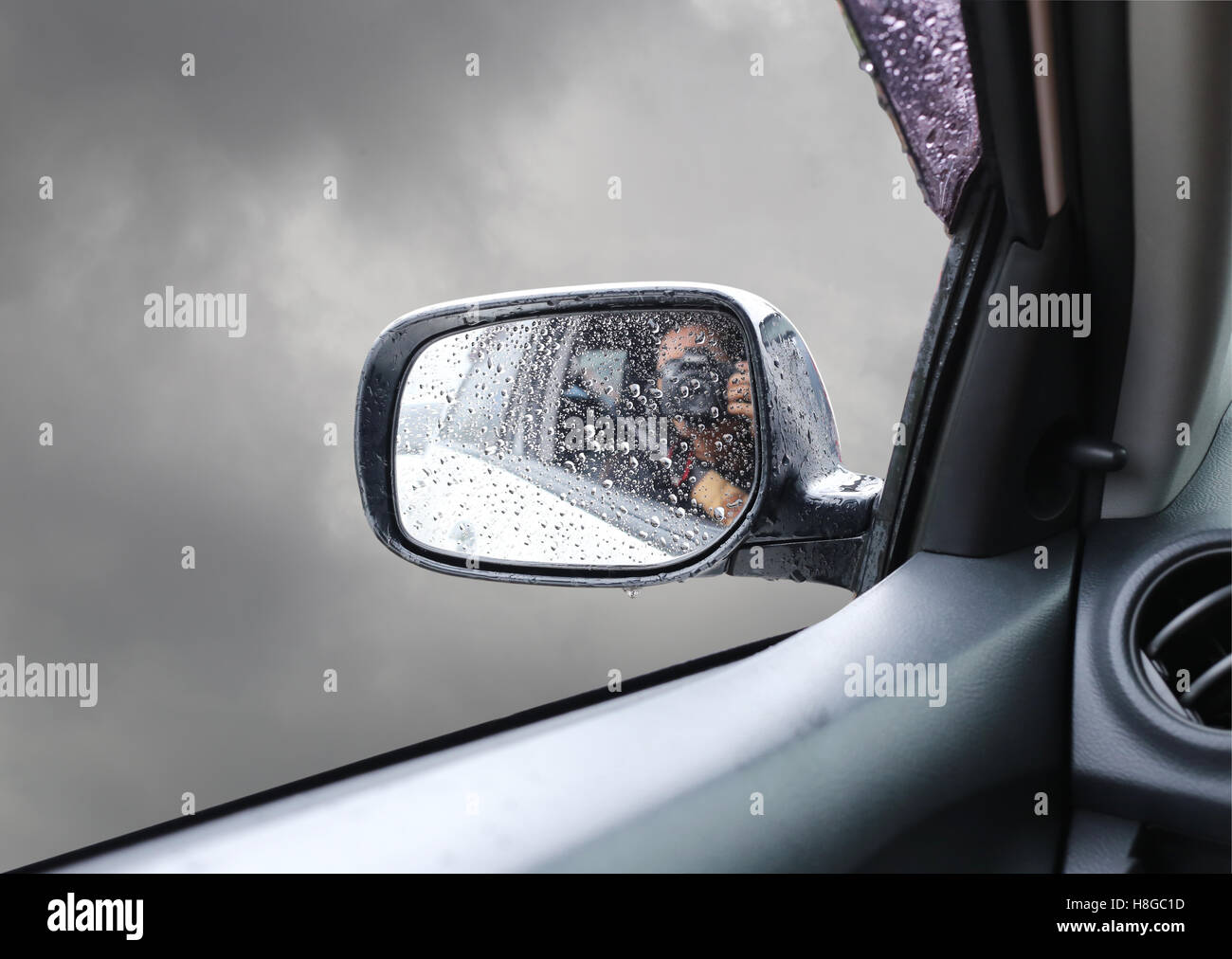Aufgrund der Regen fällt auf den bewölkten Himmelshintergrund ist Spiegel Beiwagen mit Wasser nass. Stockfoto