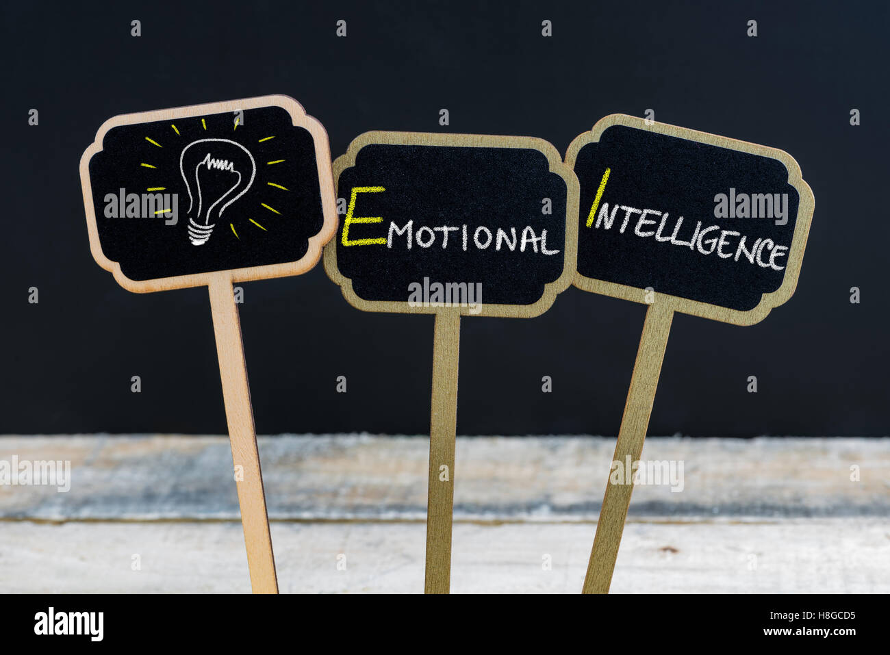 Konzept-Nachricht emotionale Intelligenz und Glühbirne als Symbol für die Idee, die auf hölzernen Mini Tafel Etiketten mit Kreide geschrieben Stockfoto