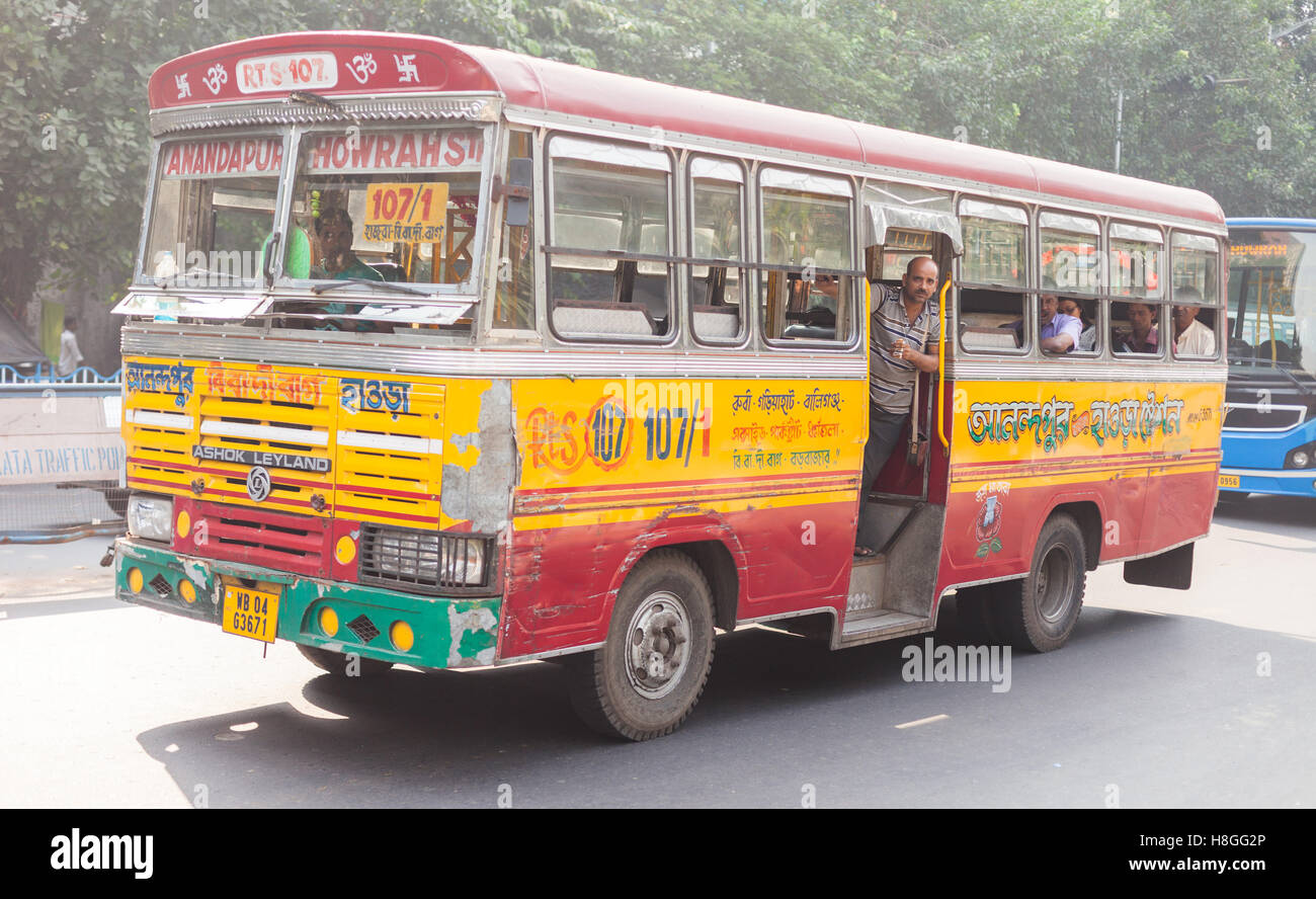 KOLKATA, Indien - 22. Oktober 2016: Ticket Collector lehnt sich aus dem Bus als bunt bemalte Local bus-Geschwindigkeit durch die Stadt auf O Stockfoto