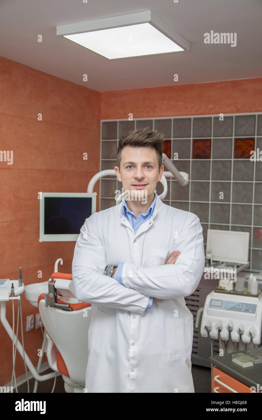 Junge männliche Zahnarzt über Arztpraxis Hintergrund Stockfoto