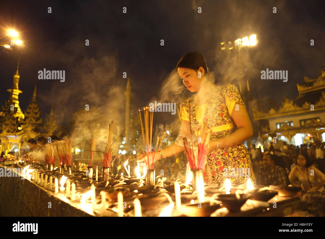 Yangon, Myanmar. 13. November 2016. Eine Frau Lichter Kerzen auf Myanmars Tazaungdaing Volksfest an der Shwedagon-Pagode in Yangon, Myanmar, 13. November 2016. Das Tazaungdaing-Festival, auch bekannt als das Festival of Lights am Tag des Vollmonds im achten Monat des traditionellen Myanmar Kalenders fällt in Myanmar als nationaler Feiertag gefeiert und markiert das Ende der Regenzeit. © U Aung/Xinhua/Alamy Live-Nachrichten Stockfoto