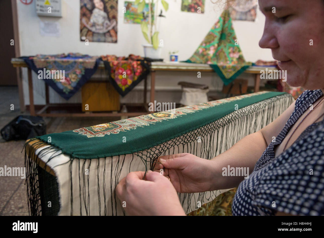 Eine Frau strickt manuell Knötchen auf einem traditionellen Pavloposadsky Schal in einer Textilfabrik in der Region Moskau, Russland Stockfoto