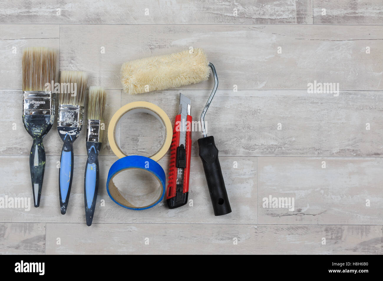 Malen Sie, Pinsel, Farbroller, Messer und Klebeband auf eine shabby Stil Holz Boden Stockfoto